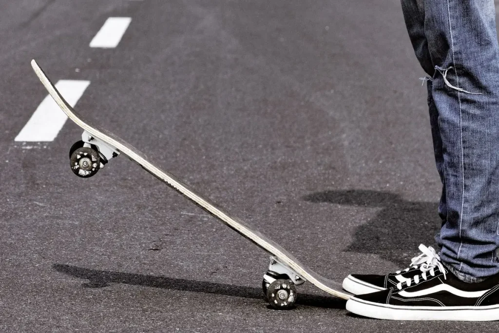Close-up of a skateboarder balancing on an asphalt road
