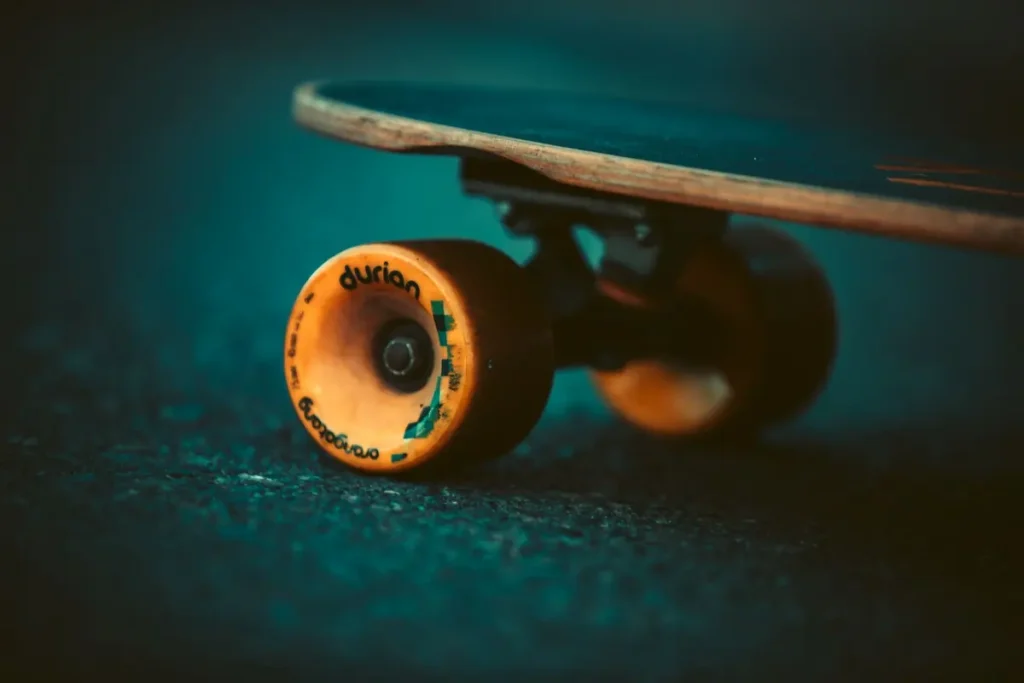 Close-up of a skateboard's orange wheel on pavement
