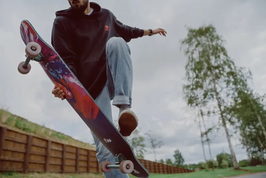 A young man doing a trick on a colourful skateboard outdoors