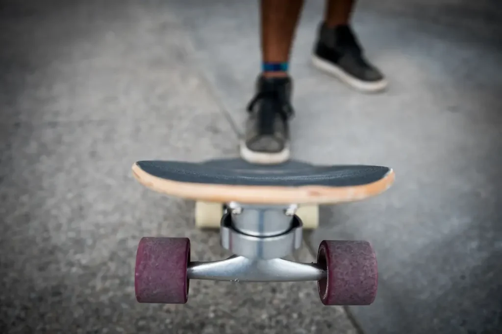 Close-up of a skateboard's trucks and red wheels on pavement