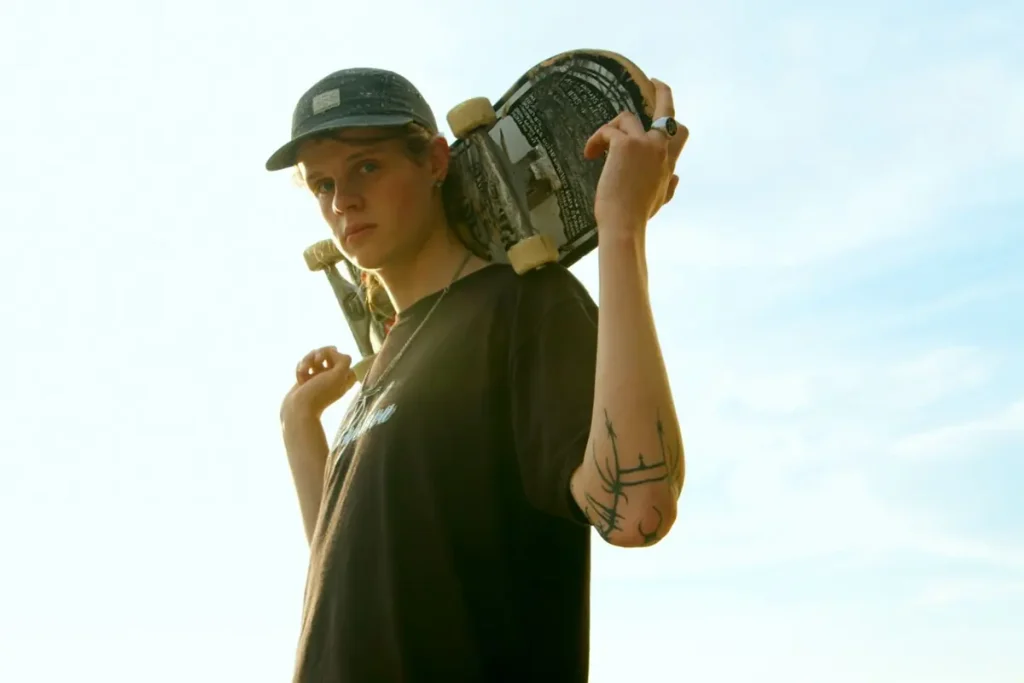 A young man with a skateboard on his shoulder
