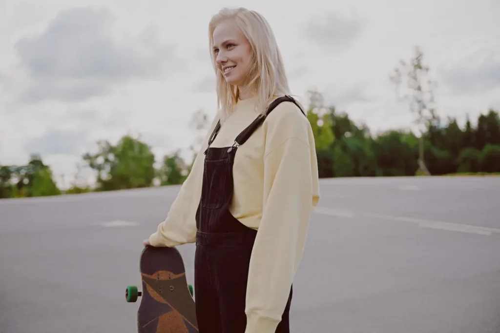 A young woman holding a longboard and smiling on a sunny day