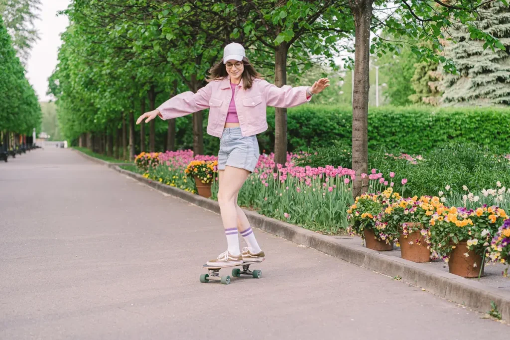 A young woman skateboarding along a park path lined with flowers