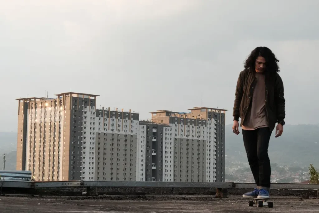 A young skateboarder on a rooftop with a city skyline behind