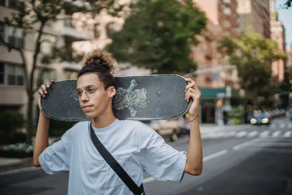 A young skater holding a skateboard on a city street