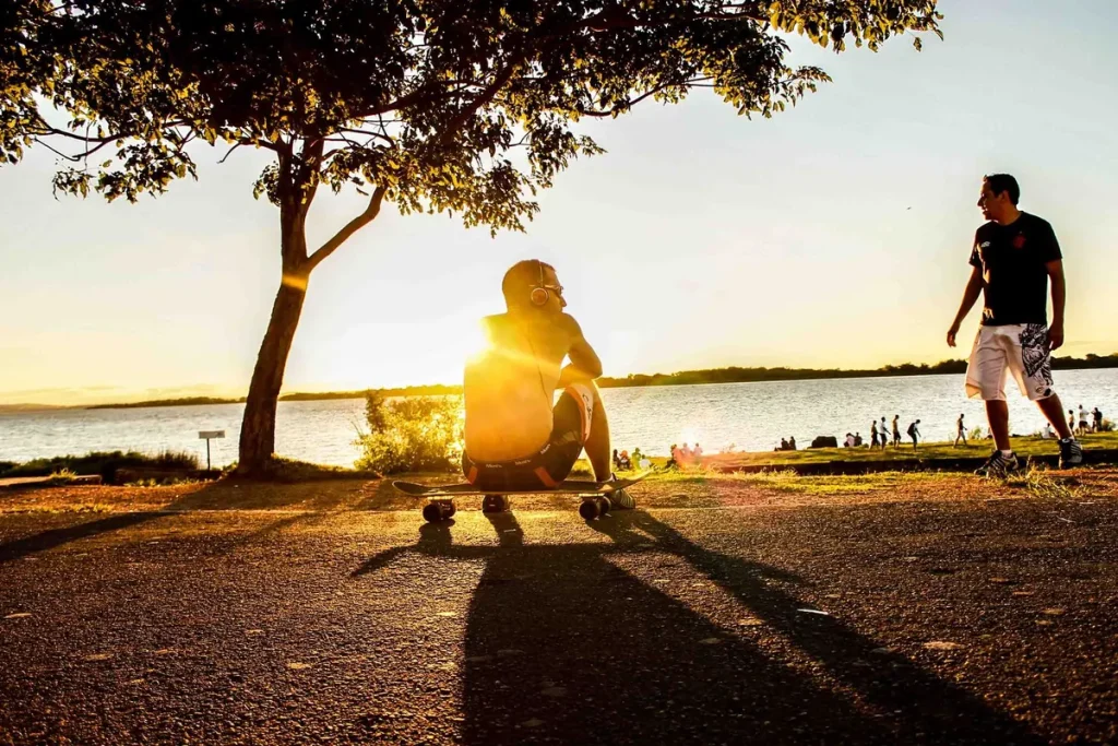 Skateboarders by the water at sunset