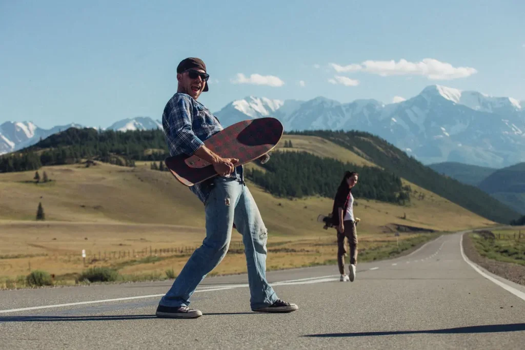 A man carrying a skateboard on a mountain road