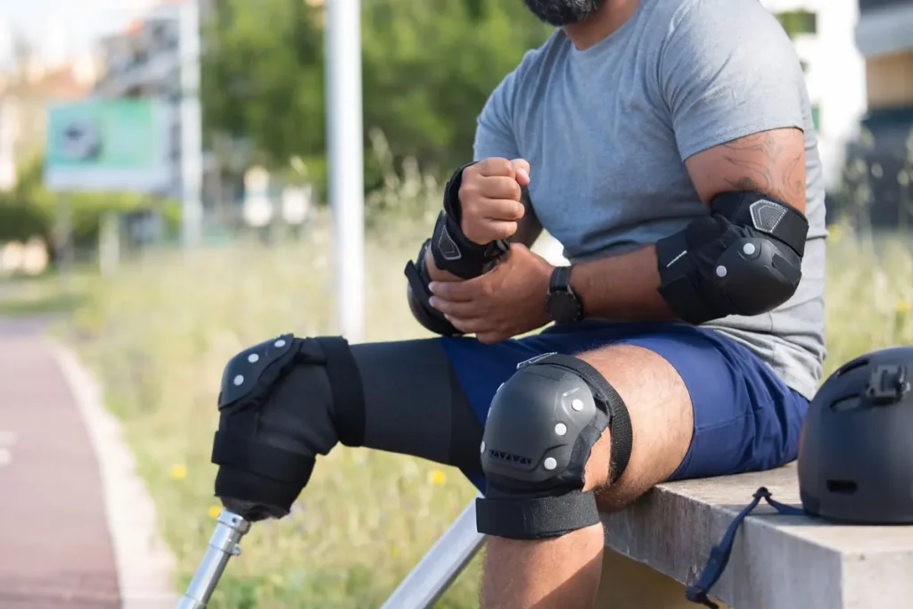A man wearing knee and elbow pads, getting ready to skate