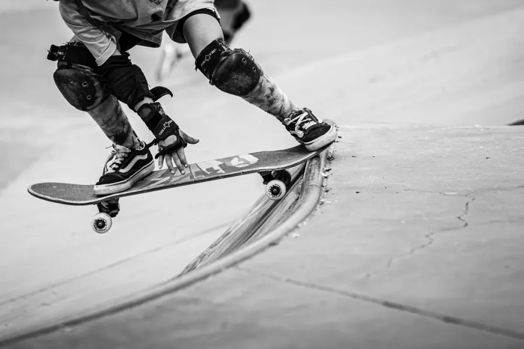 Black-and-white photo of a skateboarder in knee pads at a skatepark