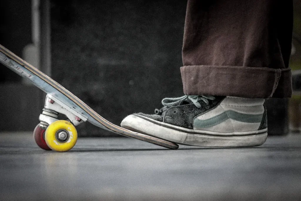 Close-up of a skateboard and a sneaker on a city street