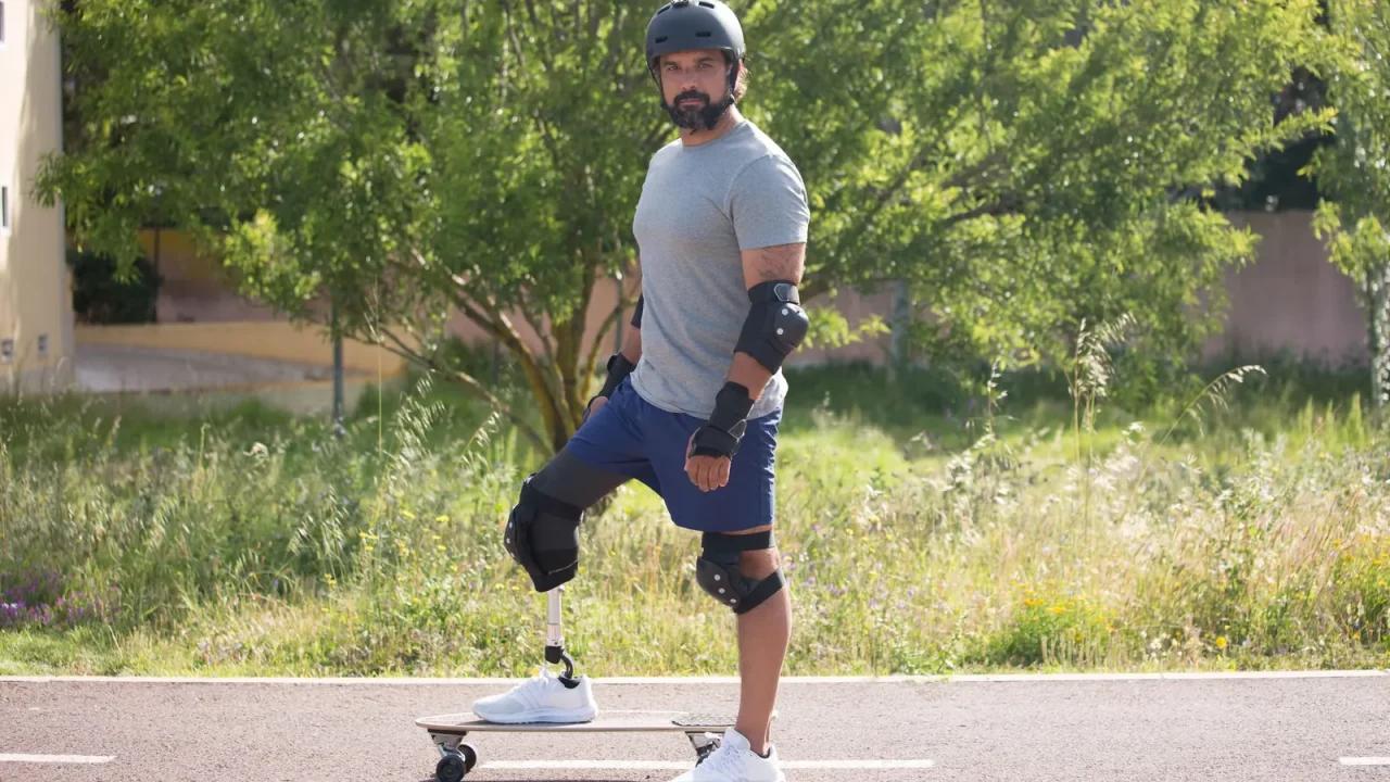 A skateboarder with a prosthetic leg riding a sunny street