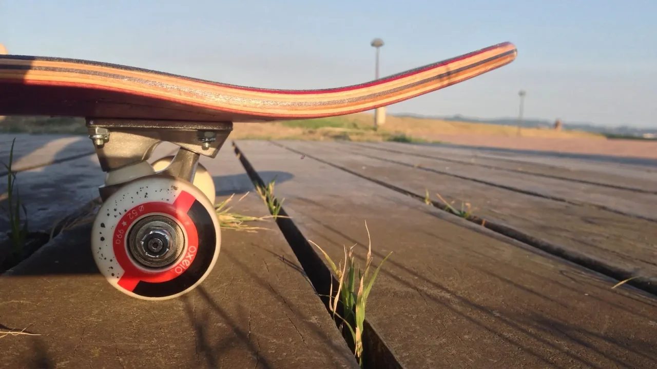 Close-up of a skateboard wheel on a wooden boardwalk at sunset