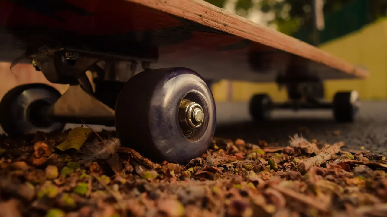 Low-angle view of skateboard wheels among dirt and fallen leaves
