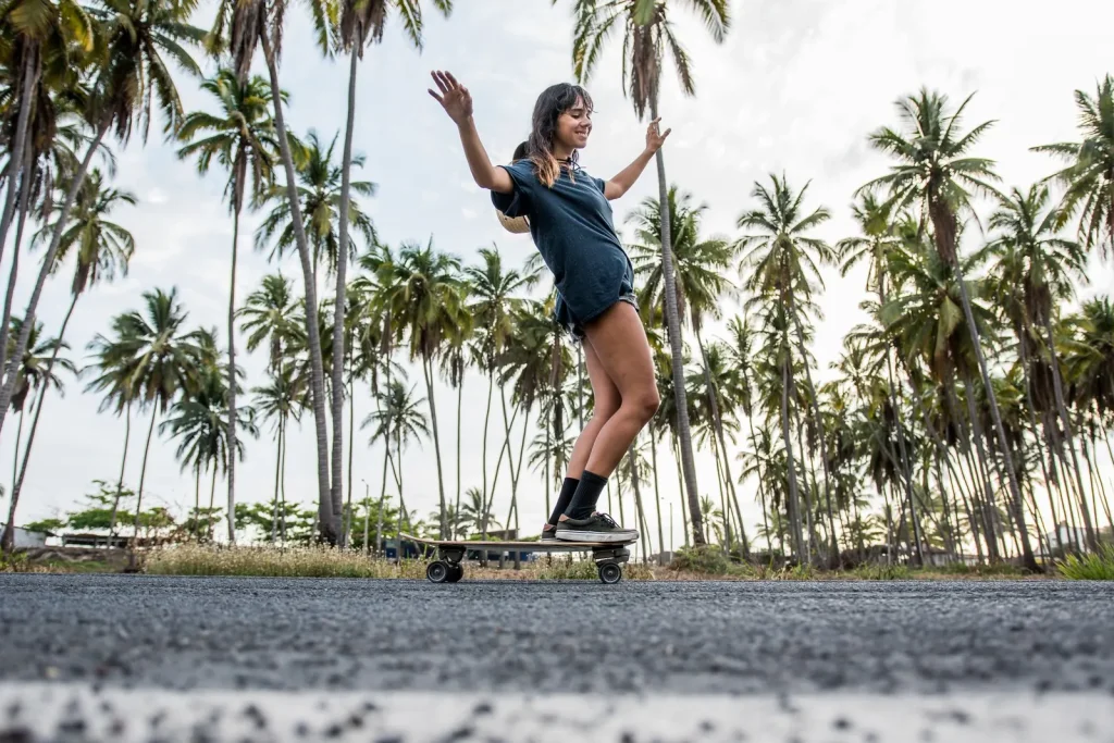 Woman cruising on a longboard along a road lined with palm trees